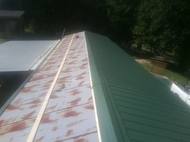 Old rusted panels beside newly installed green metal roofing — Wind Damage Roof Repair by Roofing Brothers in Hayden