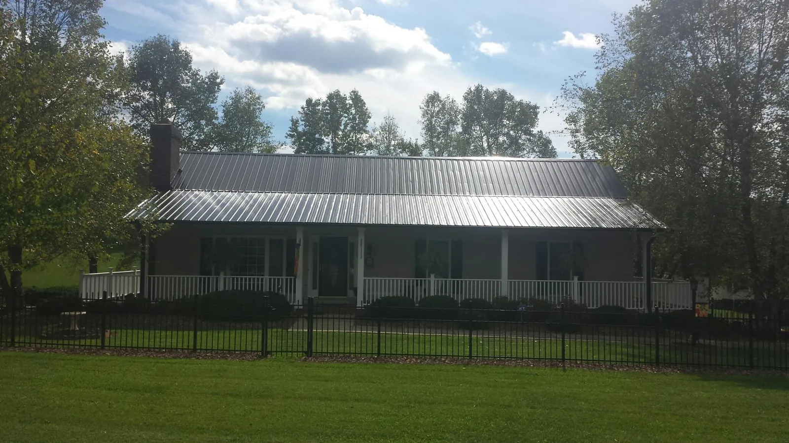 Gray metal roof on a brick ranch with a full width front porch — Gutter Guard Installation work by our crew in Hayden